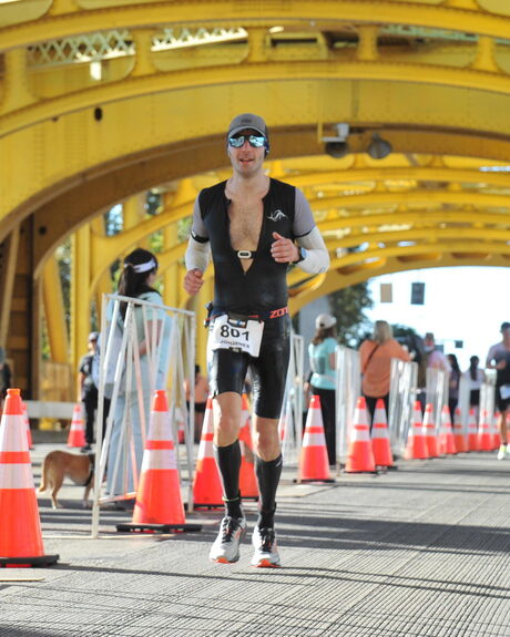 Johannes Otterbach running across the yellow Tower Bridge in Sacramento during Ironman California